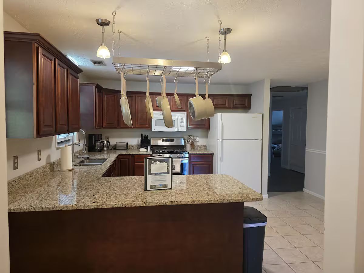 Family Times Cabin kitchen with wooden cabinets, a refrigerator, stove and counter seating.